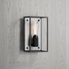 Elegant wall light. Black metal frame with a white marble backplate. The light is turned on. Light panel on the wall 