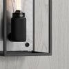 A close up of a black and white wall light. Black metal frame and a white marble backplate. The light is turned on. Light coloured panel on the wall.