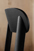 A close up of a black dining chairs backrest. Backrest has a beautiful curve to it.