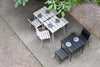 Black and white outdoor furniture in a beautiful garden. Grey plates have been set on the tables. View from above.