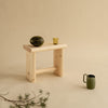 Studio image. Still life. Beige background. 002 Ast stool. A jug on the floor in front. A glass and a coconut on top of stool
