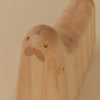 A rocking toy made from pine in the shape of a seal. Close up image of its head and face. Two small eyes and snout. Beige background.