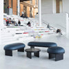 Soft and sensual high quality danish furniture in a large public space. Two benches, a pouf and a small sofa table.legs are in black wood. Seats are upholstered with dark blue leather. Black marble top on sofa table.