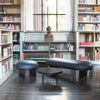 Elegant danish designer furniture in an old and beautiful library. A pouf, a bench and a sofa table. Frames of the furniture are made from black wood. Seats are upholstered with dark blue high quality leather. Dark wooden floors.