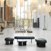 Interior shot. Very large space with high ceilings. Danish designer furniture. Two benches, a pouf and a small sofa table. All furniture have black wooden legs. The seats of the benches and pouf are upholstered with dark blue high quality leather. Sofa table with a dark marble top.