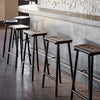 Black minimalistic barstools situated next to a grey bar. Concrete floor.