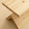A close up of one end of a solid pine bench. Beige background.
