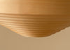 A close up of a classic Scandinavian pendant light. Light is made from bendt pine veneer. Pale beige background. Light is turned off.