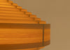 A close up of a warm Scandinavian pendant light. The light is made from thin, bendt pine veneer. Light is turned on.