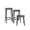 Black on black minimalistic design. Barstool, counter stool and stool. Black metal legs and black wooden seat. White background.