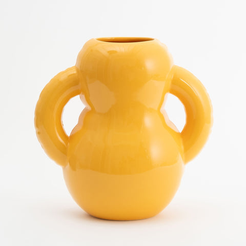 A beautiful and curvy, yellow vase made from glossy ceramics. White background.