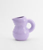 A super cute ceramic water jug in glossy mauve colour. White background.