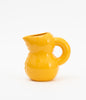 A cute, soft shaped, yellow ceramic water jug. White background.