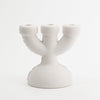 A cute, three spoke candlebra in white, matt ceramic. White background.