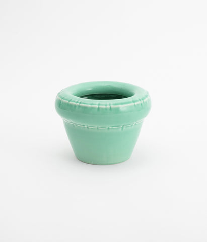 Cute and tiny flower pot. Pastel green and glossy ceramic. The planter is empty. White background.