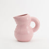 A super cute jug in pink and glossy ceramic. White background.