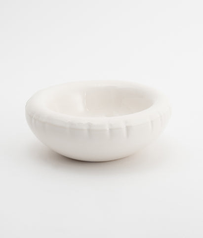 A round, white ceramic bowl on a white background. The bowl is empty.