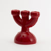 A super cute and almost cartoonish candlebra for three candles. The candlebra is in the colour burgundy and the background colour is white.