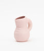 A cartoonish and cute ceramic jug in pale, pink colour. Background is white.