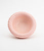 A pale pink, rounded ceramic bowl on a white background. The bowl is empty.