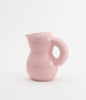 A pretty pink and glossy ceramic jug on a white background.