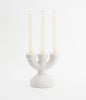Matt, white, three spoke ceramic candlebra. White candles. White background. Candles are lit.