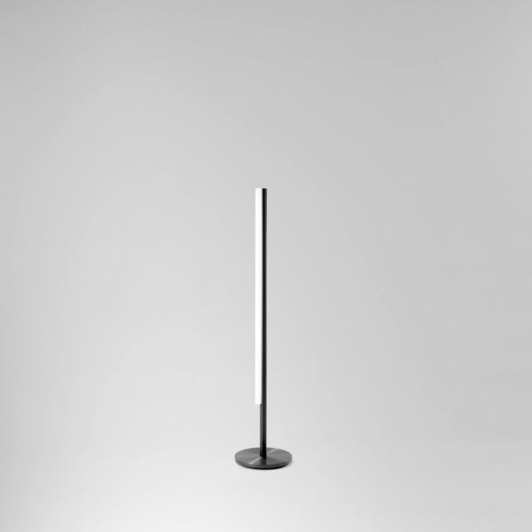 Grannur og fágaður gólflampi úr svörtu satin áli frá Michael Anastassiades. Ljós grár bakgrunnur.