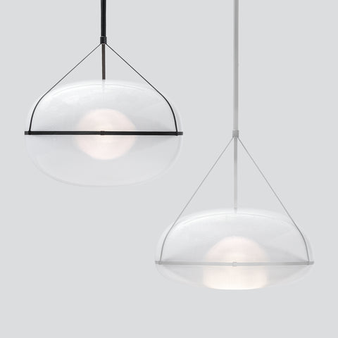 Two gorgeous, large pendant lights next to each other. White background. The light on the left is slightly higher up and has a black suspension. The pendant on the right which is lower has white suspension.