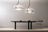 Two large spherical pendant lights hanging next to each other above a modern black dining table. White wall in the background.