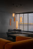 Modern living room with orange pendant lights and a large window.