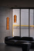 Modern interior with a black sofa, large window and cylindrical pendant lights.