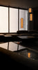 Modern interior with dark furniture, large window and cylindrical pendant lights.