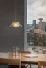 Modern interior with a glass pendant light, table, and cityscape view.