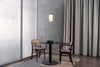 Small dining area with a round table and two chairs against a gray wall with a light fixture.