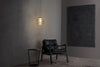 Modern black leather chair in a minimalistic room with a textured wall and pendant light.
