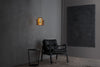 Modern black leather chair under a hanging lamp in a minimalistic room.