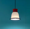 A cute little pendant light by British designer George Sowden. The light is red, white and black. Turquoise background. The light is switched on.