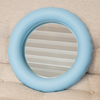 A round, pastel blue ceramic mirror rests peacefully on a light beige sofa.