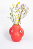 A redish, pink ceramic vase with bold and friendly shapes. White background.