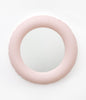 A round wall mirror from mat, pastel pink ceramics. White background.
