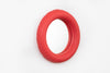 A cute, round, ceramic wall mirror on a white wall. The colour of the ceramic is redish pink.