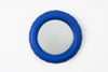 Round, navy blue ceramic wall mirror. White background.
