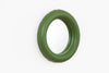 A pretty little wall mirror in mat green ceramic hangs on a white wall.