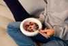 A round, white ceramic bowl filled with yoghurt, musli and berries.