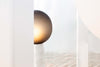 White ceramic floor lamp with dark, handmade glass defuser. White background.
