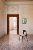 Interior shot from a large Italian estate. Elegant dining chair in black wood on the floor. Earthy terrazzo floors.