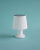 Sweet little table lamp in white with a black top. Turquoise background.