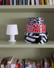A cute little, white table lamp sits on a mint green bookshelf along with a colourful tin box set.