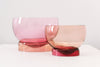 Two beautiful similar glass bowls side by side in pink tones. White background.