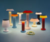 Nine, cute table lamps in pastel colours and various heights placed together as a little family. The lamps are turned on. Light blue background.